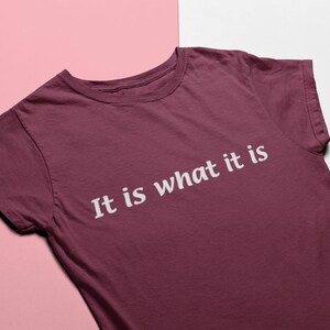 K&ouml;nnte beinhalten: Ein maroonfarbenes T-Shirt mit dem Aufdruck "It is what it is" in wei&szlig;.