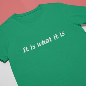 K&ouml;nnte beinhalten: Ein gr&uuml;nes T-Shirt mit dem Aufdruck "It is what it is" in wei&szlig;.