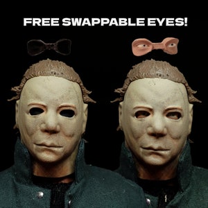 May include: Two identical masks of Michael Myers from the Halloween franchise. The masks are white with brown hair and have interchangeable eyes. The masks are shown with two different sets of eyes, one black and one brown.