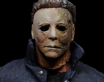 May include: A close-up of a horror movie character mask. The mask is made of a realistic material and has a distressed, weathered look. The mask is half white and half brown, with a textured surface.