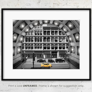 May include: A black and white photograph of a yellow taxi cab driving through a tunnel in New York City. The tunnel is lined with ornate arches and the taxi is the only color in the image.