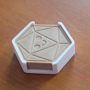 Könnte beinhalten: Ein weißer sechseckiger Untersetzer mit einem geometrischen Design auf der Oberseite. Der Untersetzer ist aus Holz und hat einen weißen Kunststoffrahmen.