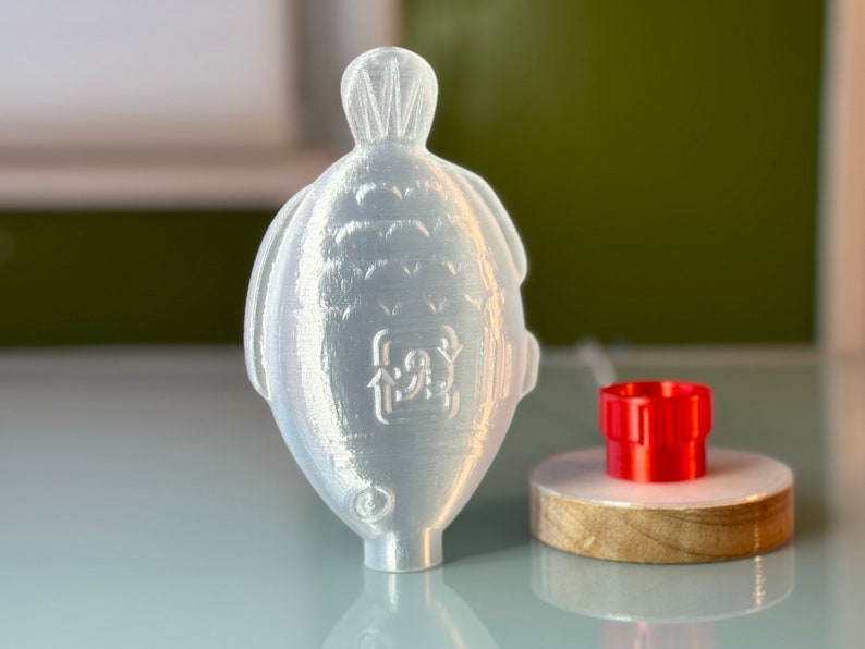 May include: A white plastic bottle with a textured surface and a recycling symbol. The bottle is sitting on a table next to a red plastic cap.