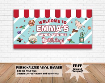 May include: A personalized vinyl banner for a candy-themed birthday party. The banner features a red and white striped awning design with candy illustrations and the text "Welcome to Emma's Candy Shoppe Birthday!" in a playful font.
