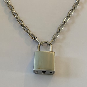 May include: A silver chain necklace with a silver padlock pendant.