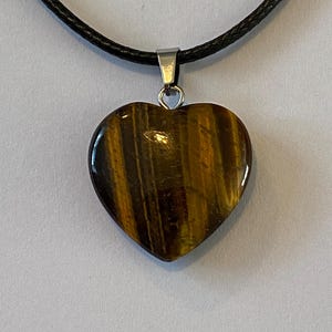May include: A heart-shaped tiger's eye pendant necklace on a black cord.