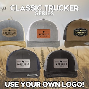Può includere: Cinque cappellini da camionista in diversi colori con una toppa marrone che presenta una stella del Texas e il testo "Lakehills Studio". Il testo "Classic Trucker Series" è nella parte superiore dell'immagine. Il testo "Use Your Own Logo!" è nella parte inferiore dell'immagine.