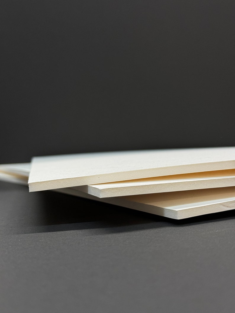 May include: Three white foam boards stacked on top of each other on a gray surface.