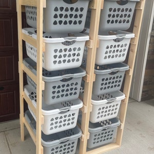 May include: A wooden laundry rack with six gray and white laundry baskets stacked on each side. The rack is made of natural wood and has a simple design.