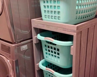 May include: A wooden laundry cart with four turquoise plastic laundry baskets. The cart has wheels and is next to a silver washing machine.