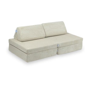 Può includere: Un divano futon in velluto a coste color crema con due schienali. Il futon è aperto e pronto per essere utilizzato come divano.