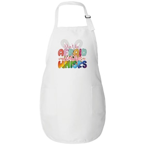 May include: White apron with a colorful graphic that says "Don't be afraid to take whisks". The graphic is surrounded by pink flowers.