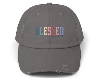 May include: A gray distressed baseball cap with the word "BLESSED" in rainbow colors and the text "Jeremiah 17:7" in black.