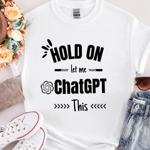 May include: White t-shirt with black text that reads "Hold on let me ChatGPT This" with arrows pointing to the text.
