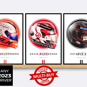 Puede incluir: Tres p&oacute;sters de cascos de pilotos de F&oacute;rmula 1 con un esquema de colores rojo, blanco y azul. Los p&oacute;sters presentan los cascos de Nico Hulkenberg, Kevin Magnussen y Esteban Ocon. Los p&oacute;sters se muestran en un estante de madera con una pegatina de oferta multicompra roja y blanca.