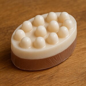 A white and brown soap bar with a textured surface sits on a wooden surface.