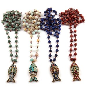 May include: Four necklaces with different colored stone beads and a gold fish pendant. The necklaces are green, white, blue, and red.
