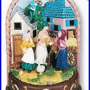 May include: A decorative musical figurine featuring a village scene with figures, a musician, and buildings. The figurine has a brown base with gold accents, a pink arch, and a detailed painted landscape.