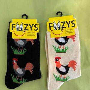 Könnte beinhalten: Zwei Paar schwarze und weiße Hahn-Socken mit einem gelben Etikett, auf dem "Foozys" und "Fun Socks For Your Feet, Serious People" steht.