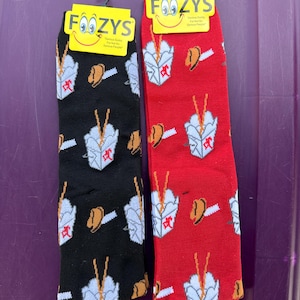 May include: A pair of black and red socks with a takeout container and fortune cookie design. The socks have the text "Foozys" and "Serious Socks For Hot So Serious People" on the packaging.
