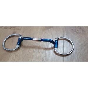 May include: A blue and silver horse bit with a twisted mouthpiece. The bit has a copper roller in the centre.