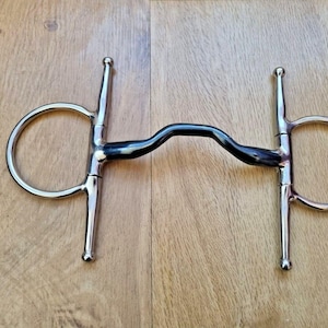 May include: A silver horse bit with a black rubber mouthpiece. The bit has two rings on either side and two jointed shanks.