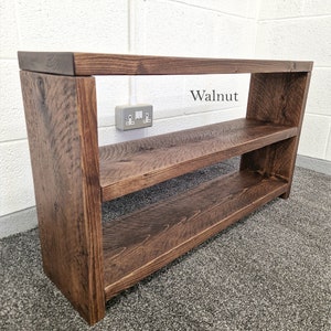 May include: A dark brown wooden shelf unit with two shelves. The shelf unit is labelled "Walnut".