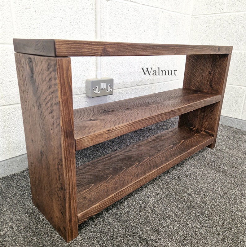 May include: A dark brown wooden shelf unit with two shelves. The shelf unit is labelled "Walnut".