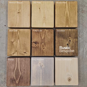 May include: Nine wooden blocks showcasing various wood stain colors. Colors include Medium Brown, Old Pine, Rustic Pine, Dark Oak, Tudor Oak, Jacobean, Walnut, Grey Washed, and Clear/Unfinished. The text "Rustic Bespoke" is visible on one block.