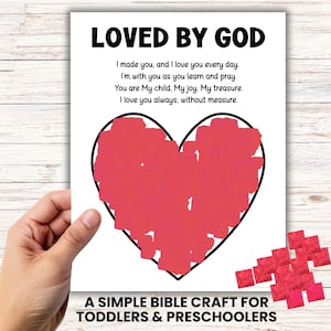 May include: A white paper with the text "LOVED BY GOD" and a red heart illustration. The text includes a poem about love and faith. The bottom of the paper reads "A SIMPLE BIBLE CRAFT FOR TODDLERS & PRESCHOOLERS."