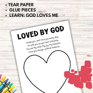 May include: A white paper with the text "LOVED BY GOD" and a heart outline. The text includes a poem about love and faith. Instructions at the top say "TEAR PAPER, GLUE PIECES, LEARN: GOD LOVES ME". Crayons are visible in the corner.