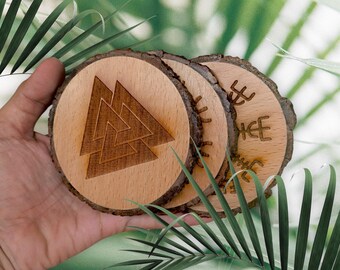 May include: Three wooden coasters with intricate designs. The first coaster features a brown triangular symbol, the second has a sun-like design, and the third has a symbol with a cross inside a circle.