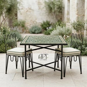 May include: An outdoor dining set comprising a square table and two chairs. The table has a green and white patterned top. The chairs have a unique wavy back design. The set is made of black metal with white cushions and green trim.