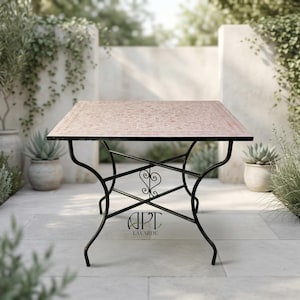 May include: A square outdoor table with a mosaic tile top and black wrought iron legs. The table has a decorative design on the legs and the text "ART LAVARDE" is visible on the table's frame. The table is set on a stone patio.