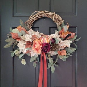 Rust pumpkin fall wreath with eucalyptus mix, beige neutral maple leaves, red aspen, orange peony, purple ranunculus and satin ribbon