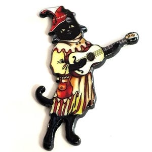 May include: A black cat dressed as a jester plays a white guitar. The cat is wearing a red and yellow jester hat, a yellow and red striped shirt, and red pants. The cat has a black tail and black shoes.