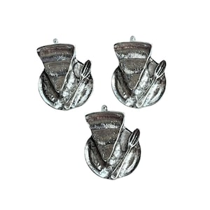 May include: Three silver charms shaped like a slice of pie on a plate with a fork.