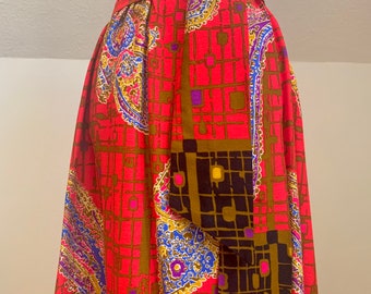 May include: A red, brown, blue, and gold patterned skirt with a self-tie belt. The skirt has a geometric and paisley design.
