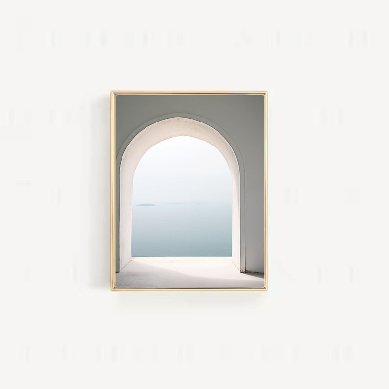 May include: A framed photograph of a white archway with a view of a body of water and a small island in the distance. The archway is framed in gold.