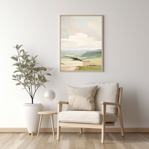 Puede incluir: Una pintura abstracta de paisaje enmarcada con un cielo azul claro, nubes blancas y colinas verdes y marrones. La pintura est&aacute; colgada en una pared blanca sobre un sill&oacute;n de madera clara con un coj&iacute;n blanco.