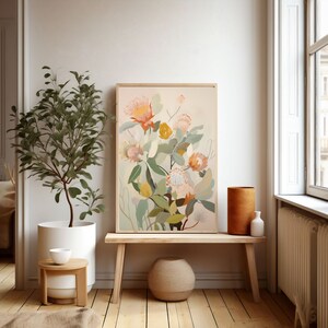 May include: A framed botanical illustration of a bouquet of pink and orange protea flowers with green leaves on a light beige background. The print is hanging on a white wall above a wooden bench.