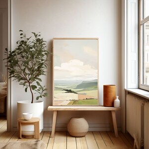 Puede incluir: Una pintura de paisaje enmarcada que representa una colina verde ondulada con una nube blanca en el cielo. La pintura est&aacute; colgada en una pared blanca en una habitaci&oacute;n con un banco de madera y una planta en maceta.
