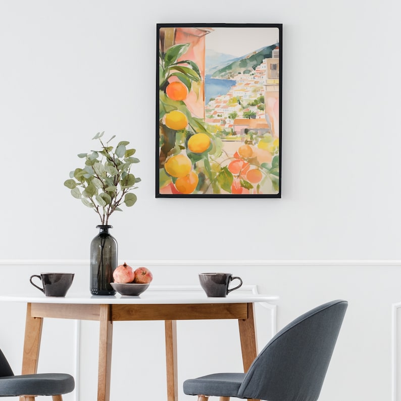 May include: A framed watercolor painting of a Mediterranean village with a citrus tree in the foreground. The painting features a view of a hillside village with white buildings and a blue sea in the background. The citrus tree is laden with ripe oranges and lemons.