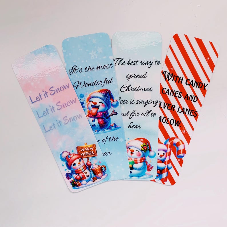 May include: Four Christmas-themed bookmarks featuring snowmen and candy canes. The bookmarks have different designs and sayings, including "Let it Snow", "It's the most Wonderful", "The best way to spread Christmas cheer is singing loud for all to hear", and "With Candy Canes and Silver Lanes Aglow".