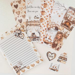 May include: A set of brown and white heart-themed bookmarks with various designs, including a couple sitting on a bench, a bridge, a fireplace, and a woman holding a cup. The bookmarks feature the text "And then one day there was you".