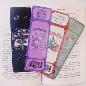 May include: Four colorful bookmarks with inspirational quotes and illustrations. The bookmarks feature a sword, a crown, an arrow, and a book. The quotes are "For every girl who had ever felt powerless", "For those fearless enough to follow their heart", "Powerless", and "Fearless".