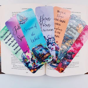 K&ouml;nnte beinhalten: Satz von zehn bunten Lesezeichen mit einem Hexenthema. Die Lesezeichen zeigen Aquarell-Illustrationen von Kesseln, K&uuml;rbissen und anderen Halloween-Bildern. Der Text auf den Lesezeichen enth&auml;lt S&auml;tze wie "Saison der Hexe", "Hocus Focus" und "Es ist Magie in der Nacht".