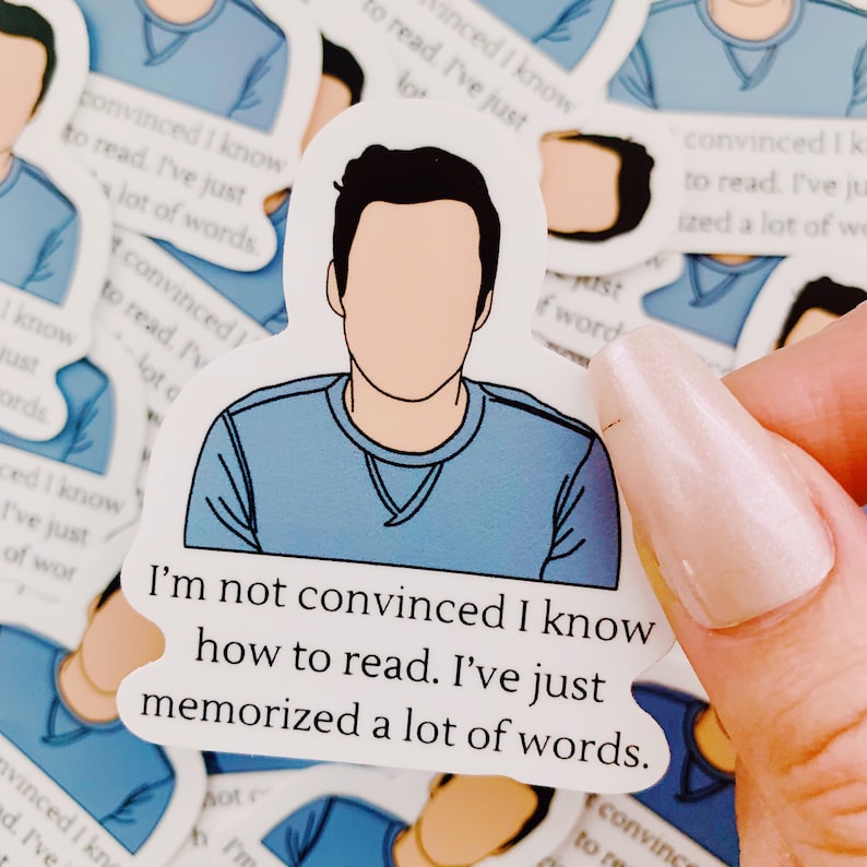 May include: A blue sticker with a cartoon illustration of a person with the text "I'm not convinced I know how to read. I've just memorized a lot of words."