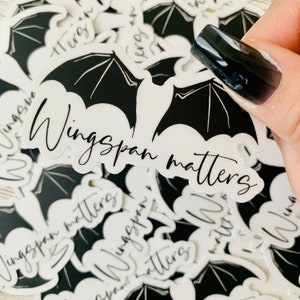 May include: A white sticker with black bat wings and the text "Wingspan matters" in a cursive font.