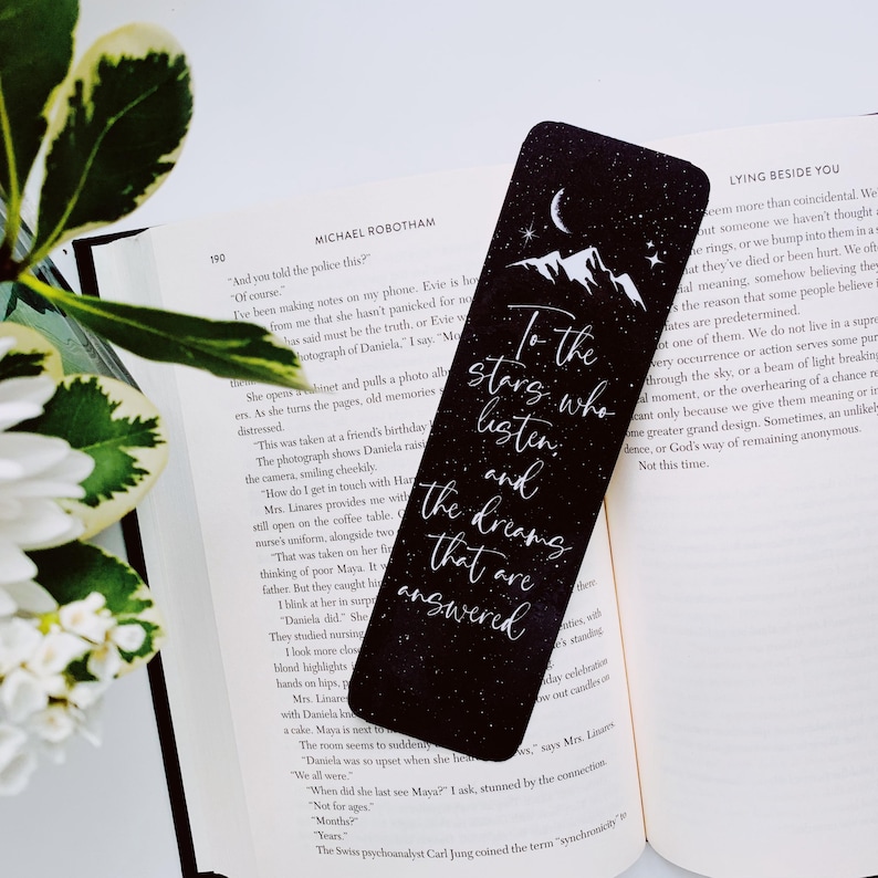 Puede incluir: Marcap&aacute;ginas negro con texto blanco y un dise&ntilde;o de cielo estrellado. El texto dice "To the stars who listen and the dreams that are answered".